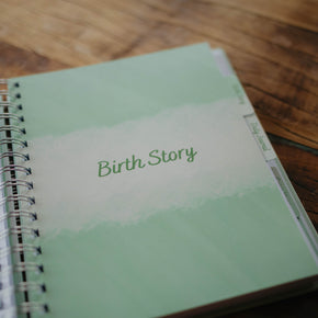 A close up of the Birth Story  section tab page in The NICU Notebook®, a light green, coil bound NICU Journal for families with a baby in the Neonatal Intesive Care Unit, on a wooden table top.