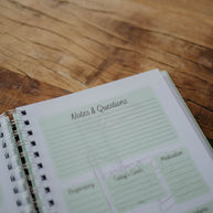 The NICU Notebook®, a light green, coil-bound NICU Journal, opened to the second daily page from the Daily Journal section. The page features unfilled boxes that hold information such as 